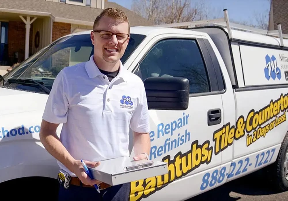 Miracle Method franchise owner/employee standing and smiling in front of his company truck.