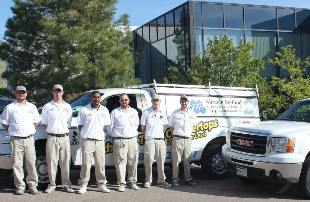 Miracle Method franchise owners/employees standing and smiling in front of a Miracle Method truck.